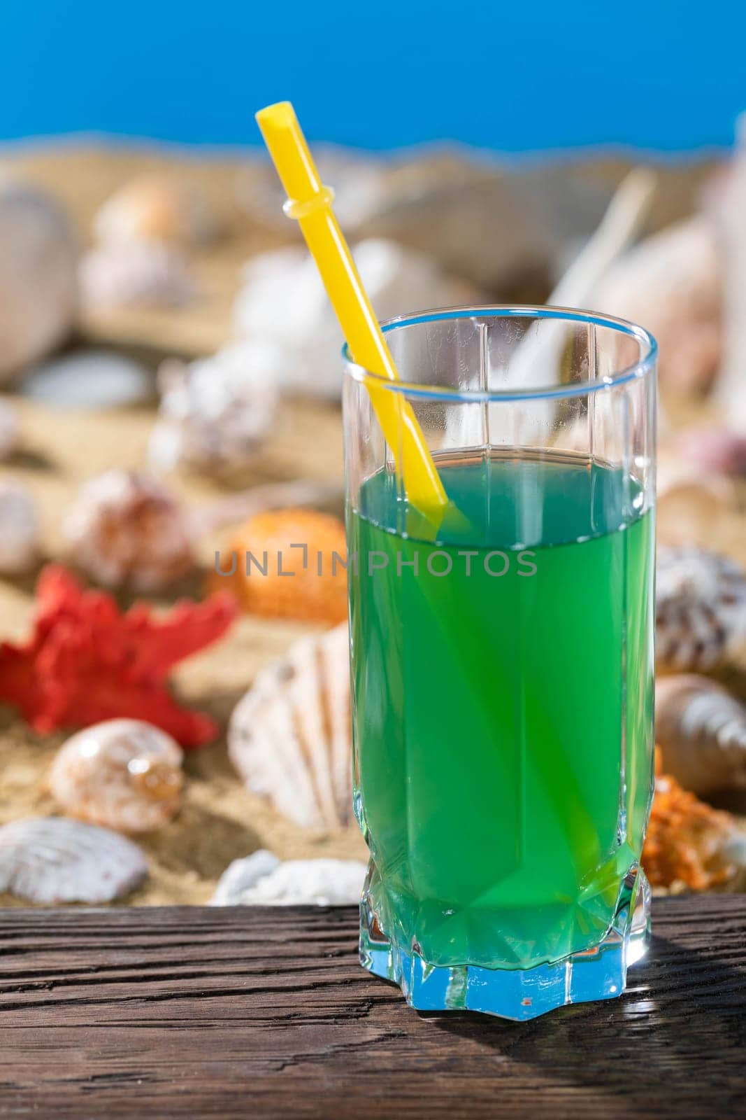 Fresh grape juice. A sandy beach on the shores of a cool sea. Brown platform board.