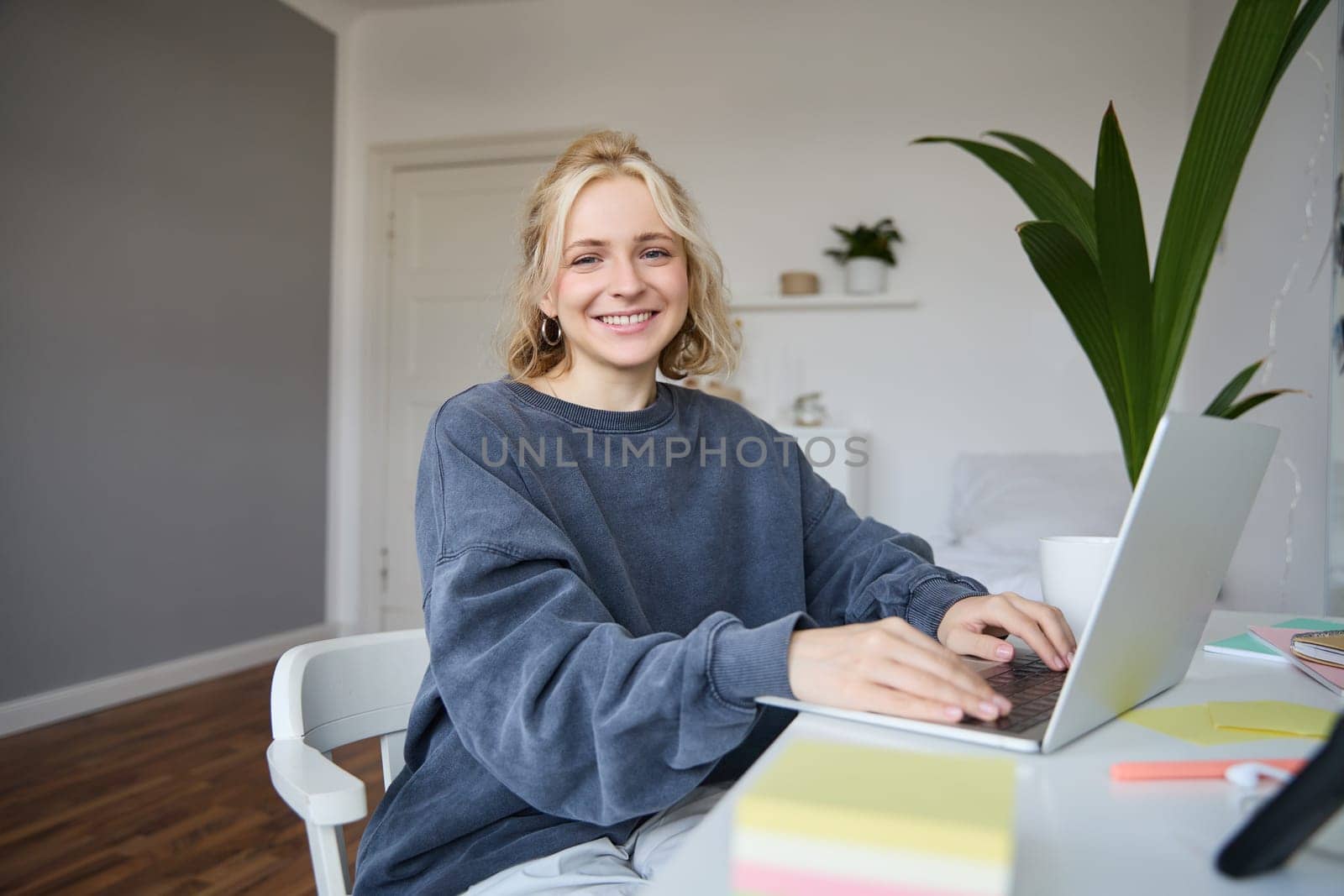 Portrait of young woman, student studying at home on remote education, working on laptop, typing on keyboard.