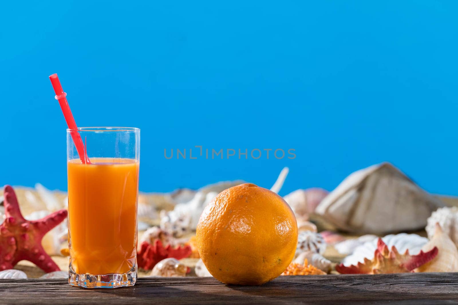 Ripe orange. Fresh orange juice. A sandy beach on the shores of a cool sea. Brown platform board.