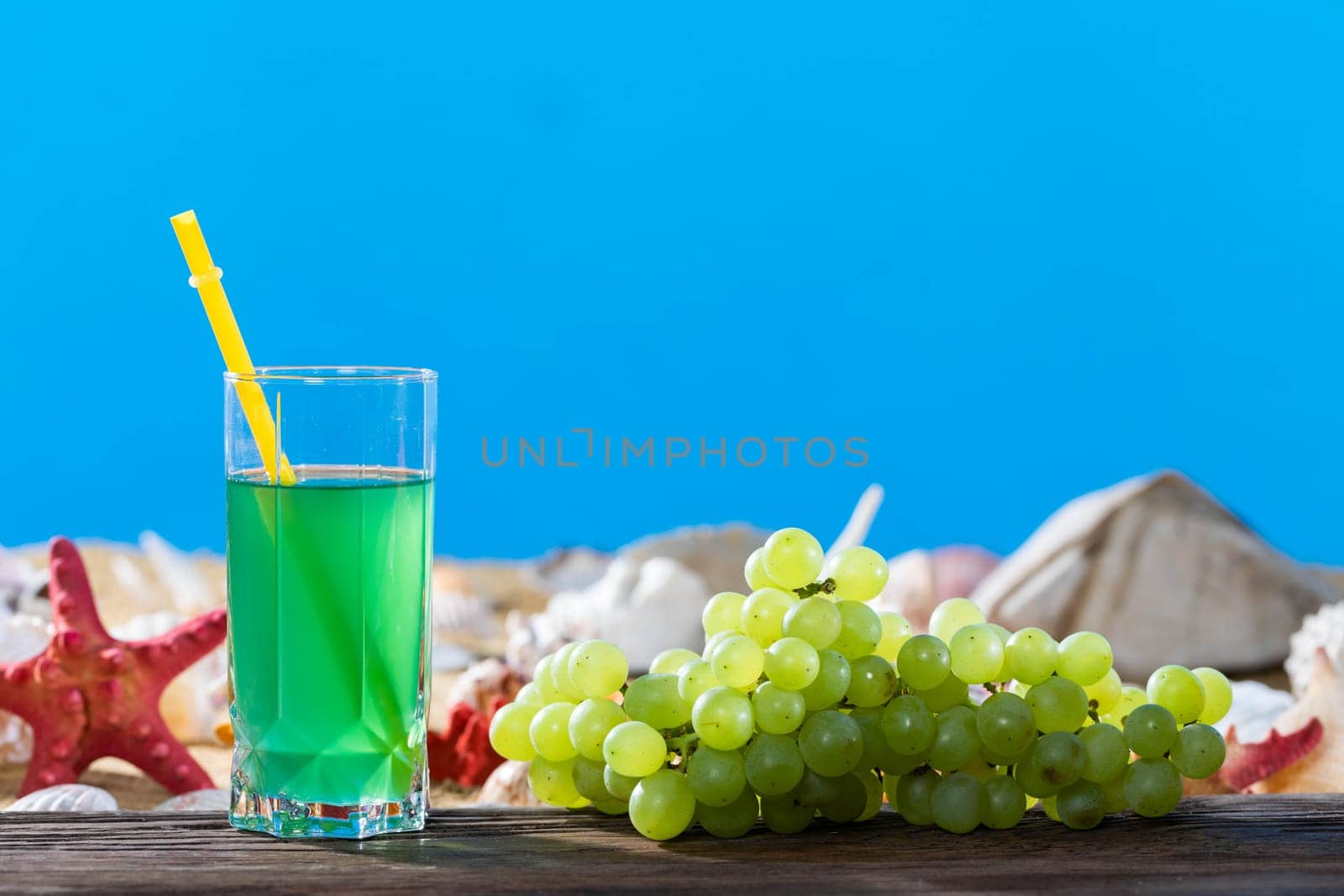 Bunch of grapes. Fresh grape juice. A sandy beach on the shores of a cool sea. Brown platform board.