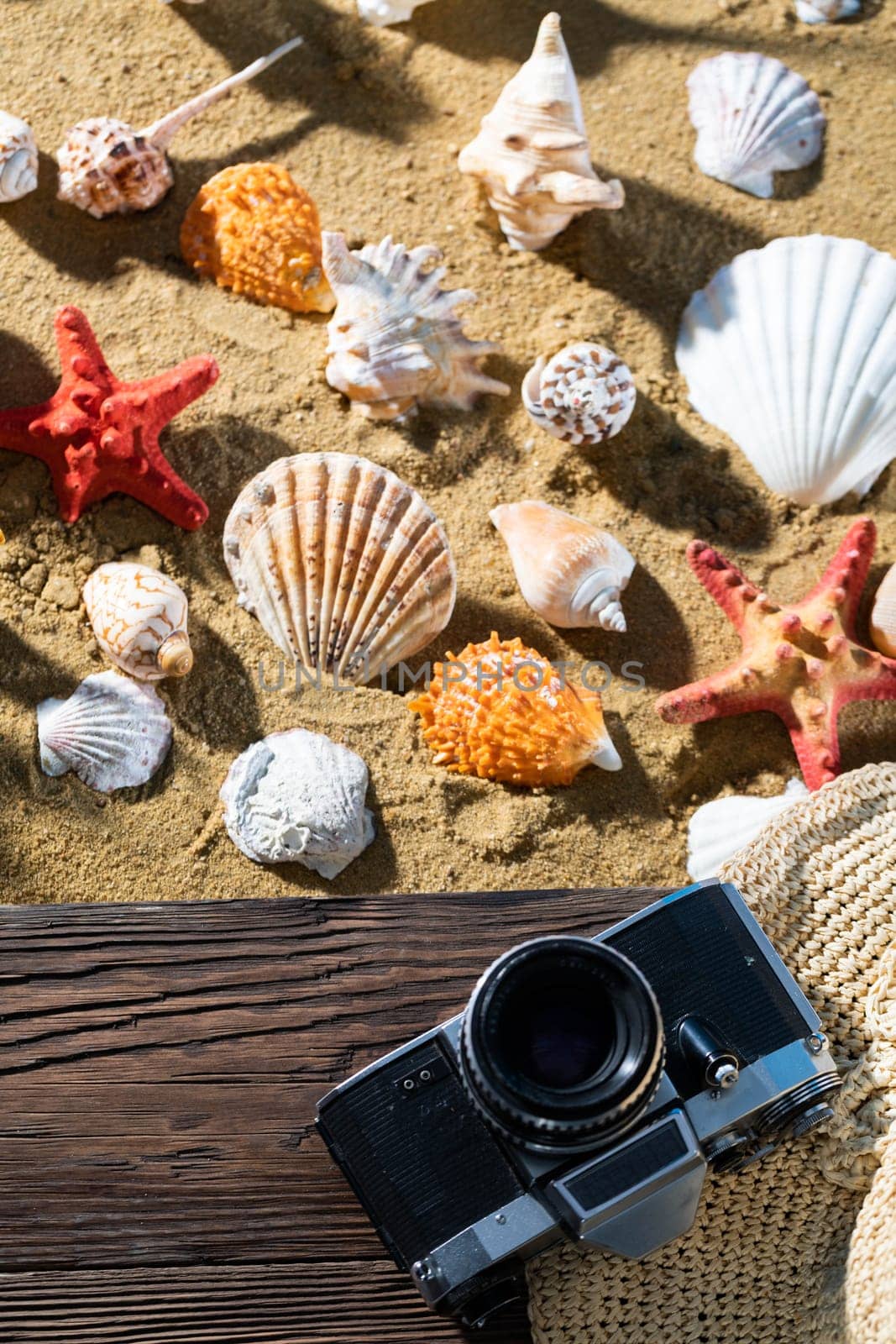 Old camera. Tourist accessories lie on the platform. Sandy shore of the sea beach.