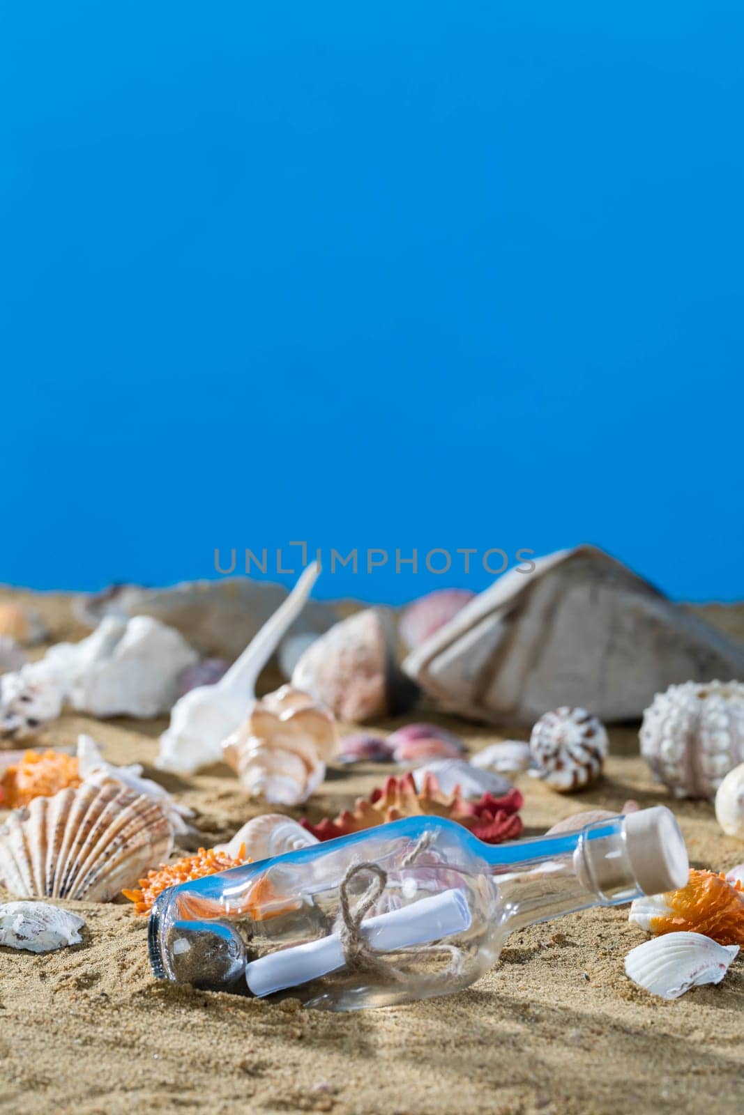 A glass bottle with a letter washed up on the beach shore. Sea beach full of shells and sand. Blue sky. by fotodrobik