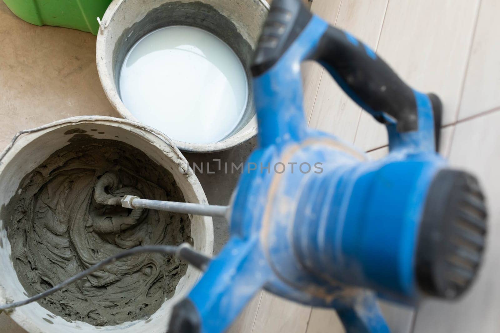 A full bucket of special tile adhesive ready for use. Dense cement-based adhesive mixer.