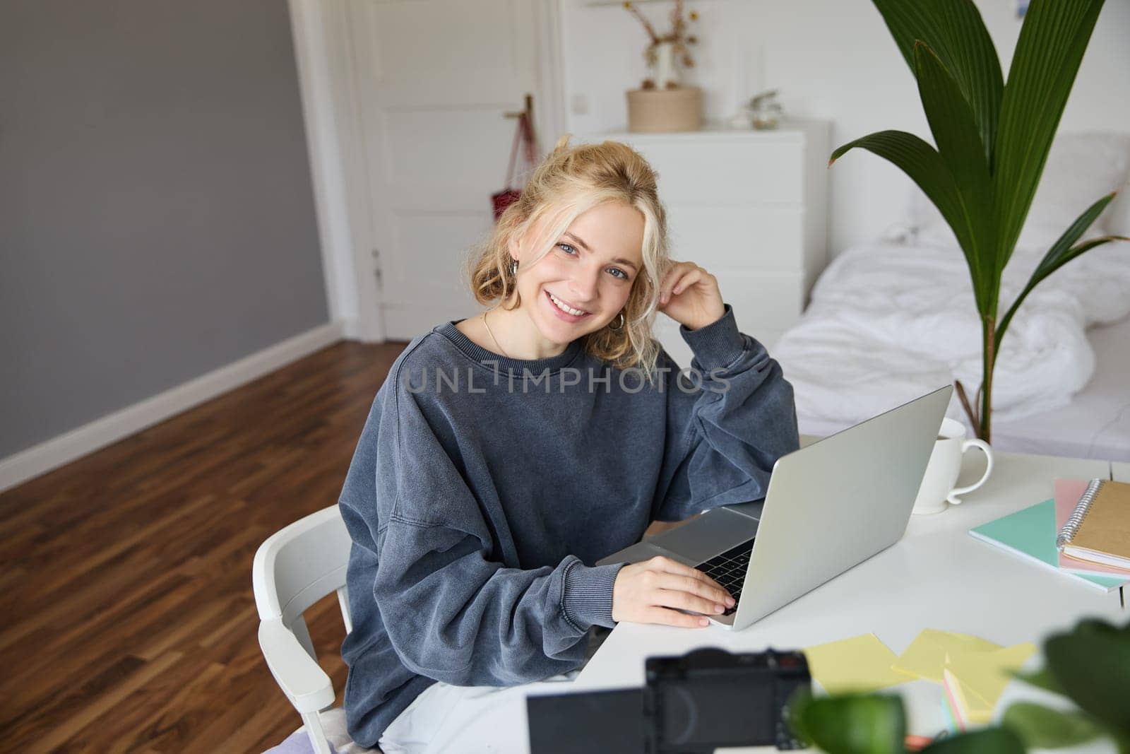 Portrait of young woman, lifestyle blogger, recording vlog video about her life and daily routine, sitting in front of laptop, talking to followers, sitting in her room.