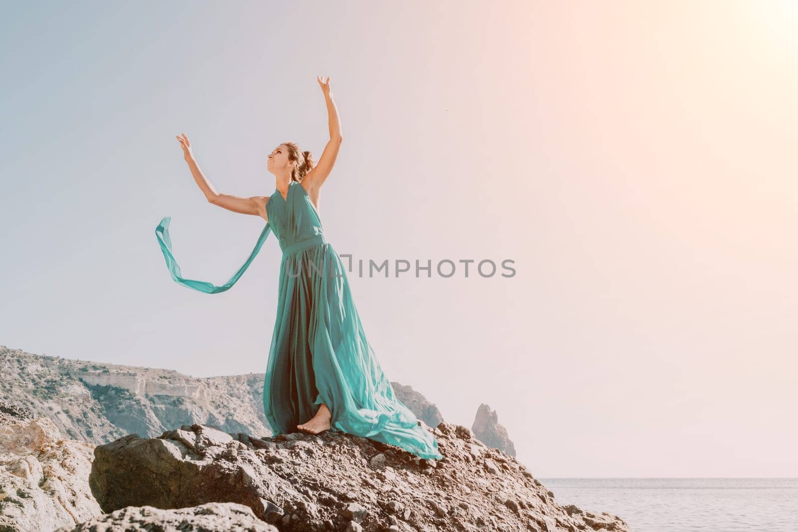 Side view a Young beautiful sensual woman with black hair in a long mint dress posing on a beach with calm sea bokeh lights on sunny day. Girl on the nature on blue sky background. Fashion photo by panophotograph