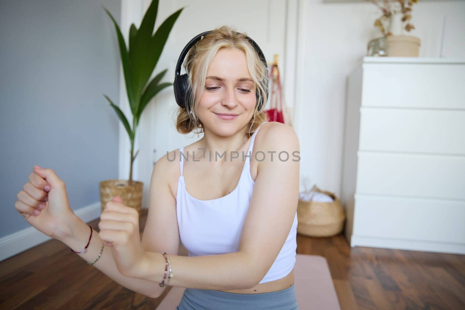 Close up of athletic young woman, cute female model in wireless headphones, dancing to favorite song, listens to music in earphones.