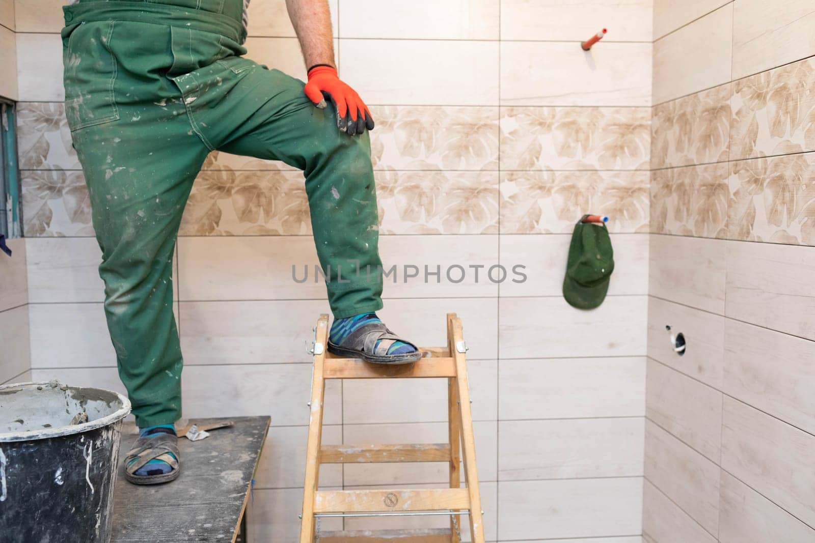 The builder took a break from work. Short rest at work standing up. Professional work footwear.