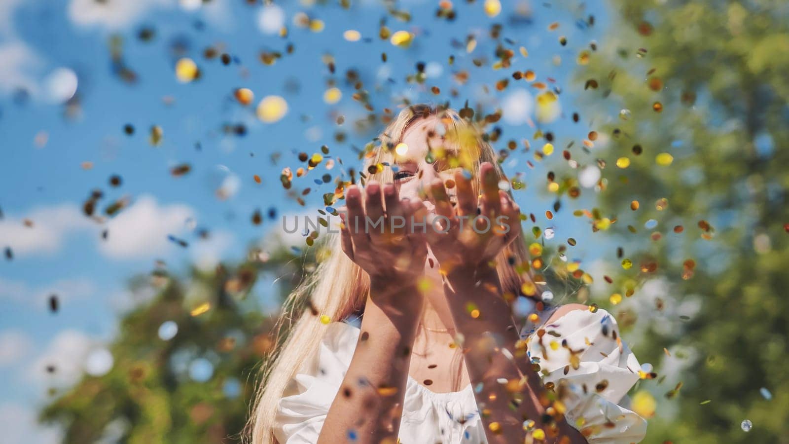 The girl blows a golden confetti out of her hands