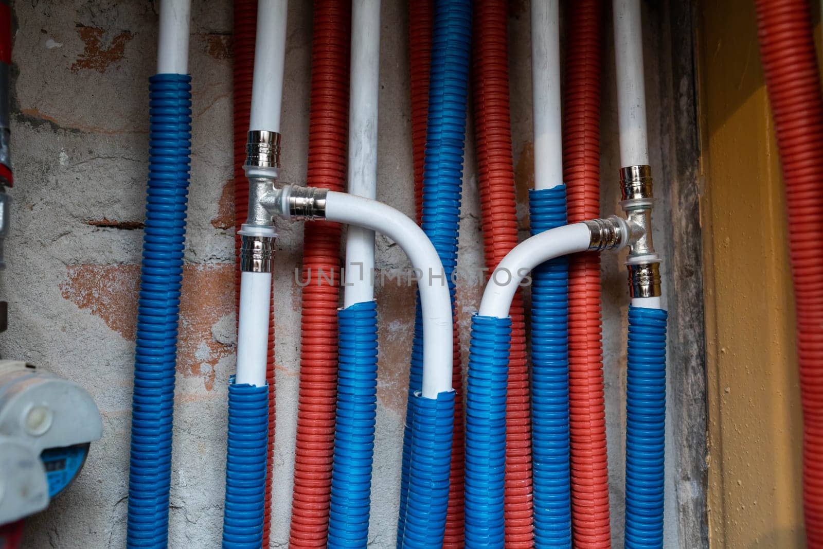 Plumbing installation in a newly designed bathroom. Water pipe in corrugated insulation in blue and red.