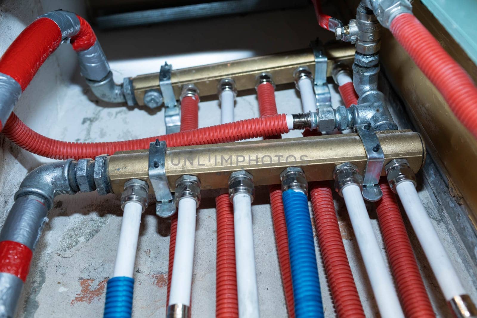 Plumbing installation in a newly designed bathroom. Water pipe in corrugated insulation in blue and red.