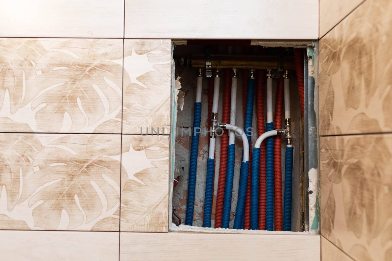 Plumbing installation in a newly designed bathroom. Water pipe in corrugated insulation in blue and red.