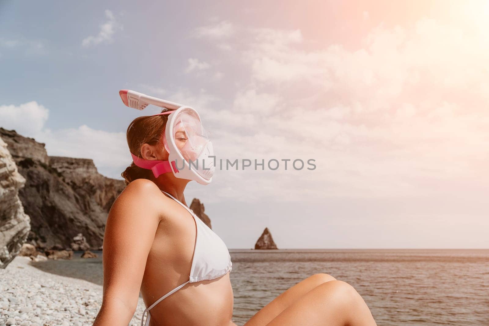 Young happy woman in white bikini put pink snorkeling mask on beach before swimming. girl having fun relaxing on beautiful beach. Beach lifestyle