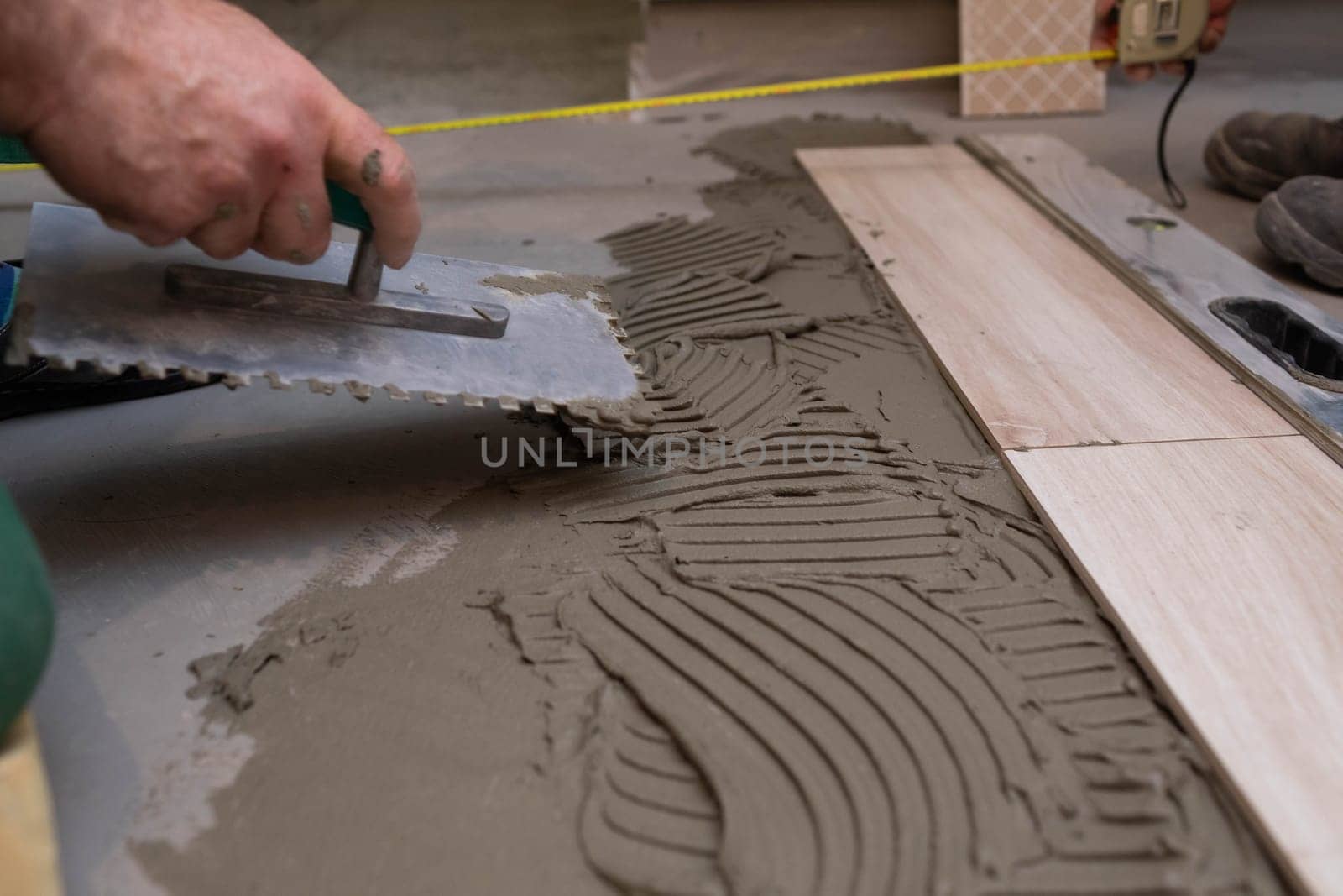 Professional construction worker laying ceramic tiles on the floor in the bathroom room.