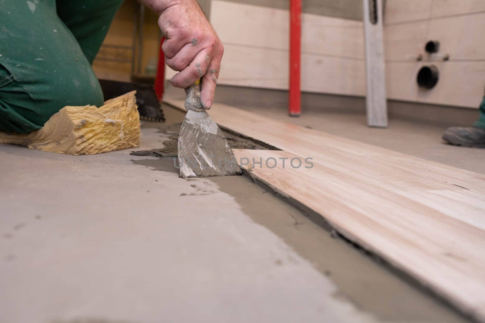 Professional construction worker laying ceramic tiles on the floor in the bathroom room.