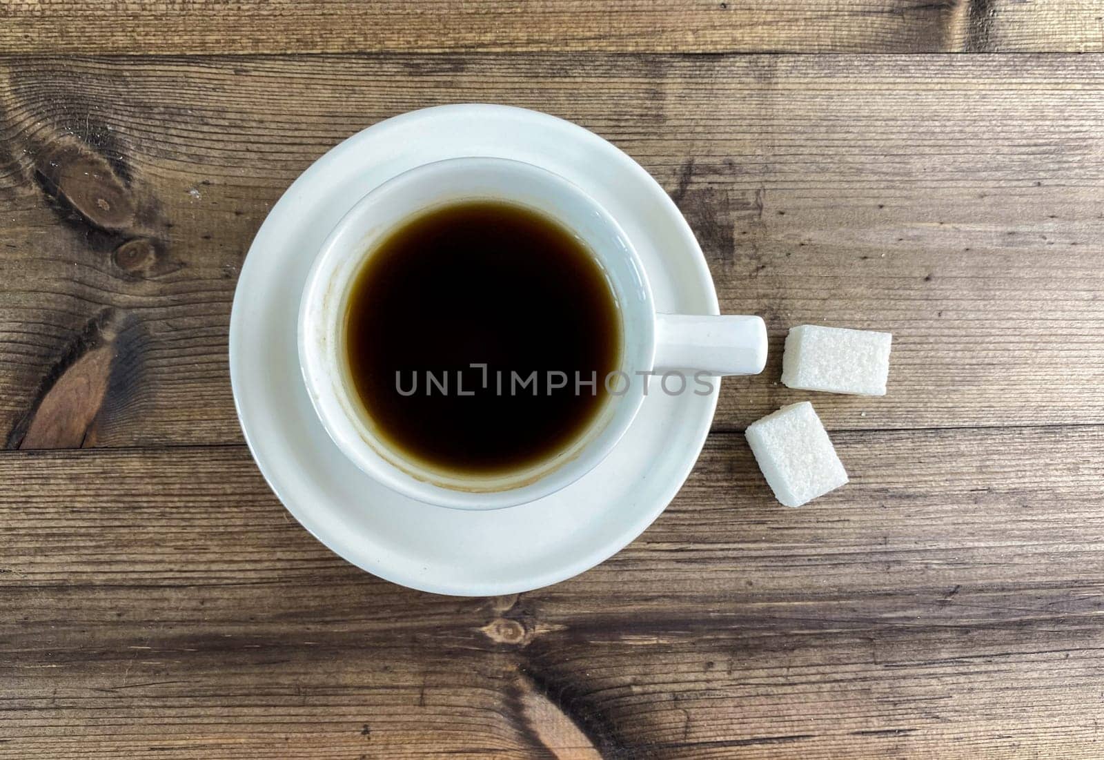 Coffee in a cup and sugar on the table, top view. Coffee in a cup with saucers and sugar on a wooden table.