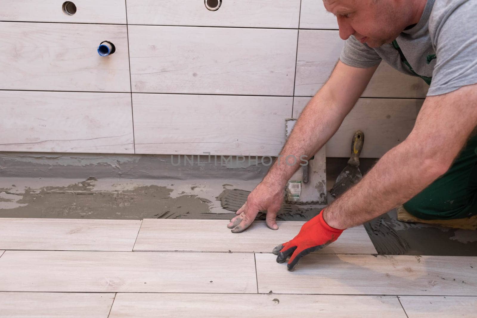 General construction worker. Adhesive for ceramic tiles. The builder glues terracotta to the floor.