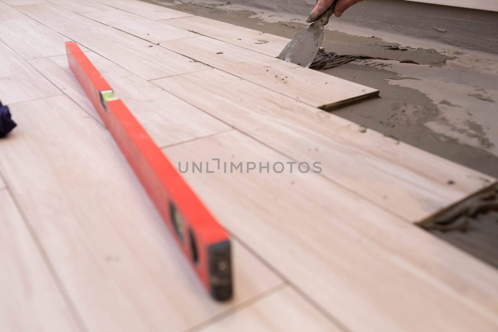 Professional construction worker laying ceramic tiles on the floor in the bathroom room.