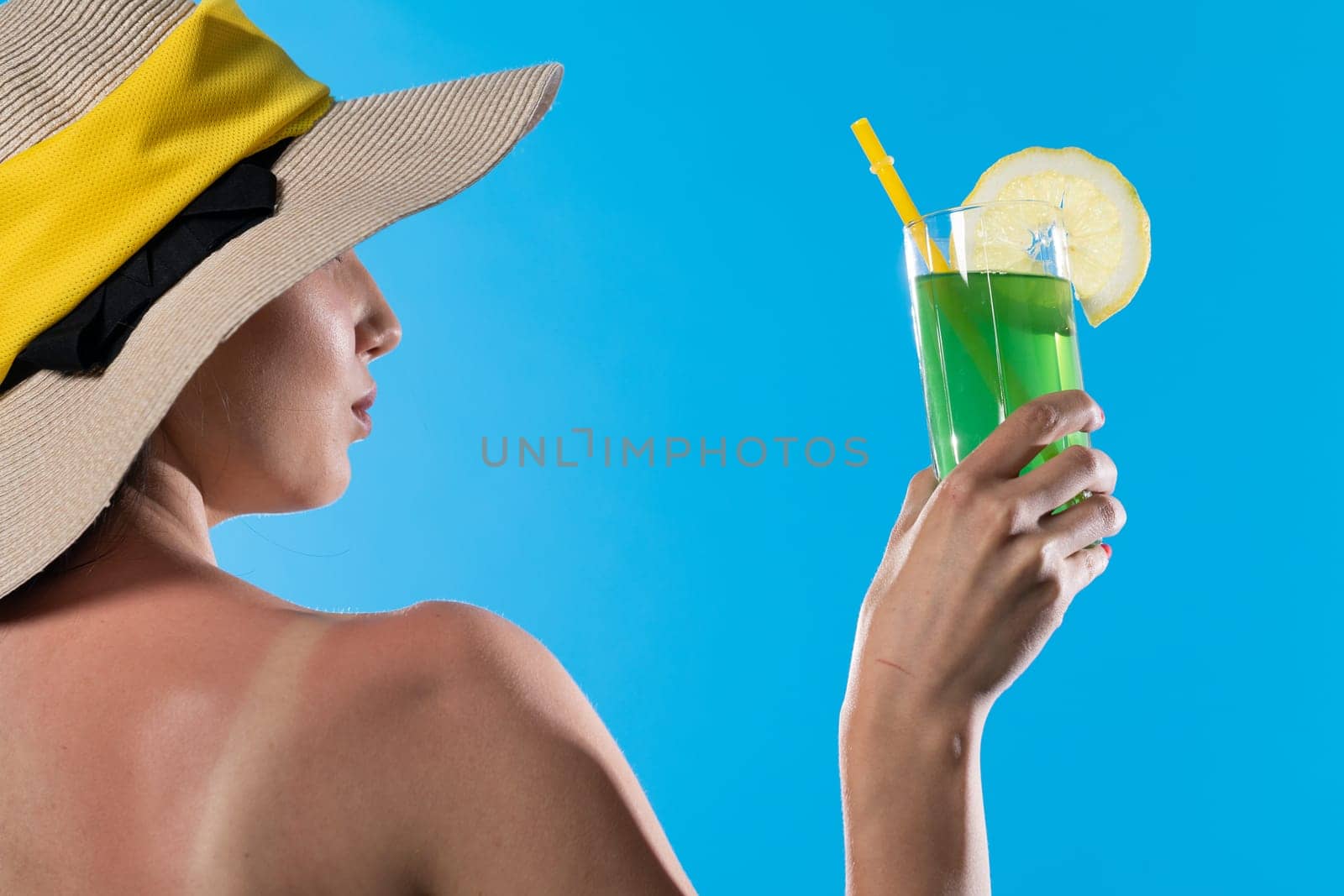 A young girl stands back to back with a cool drink in hand against the blue sky.