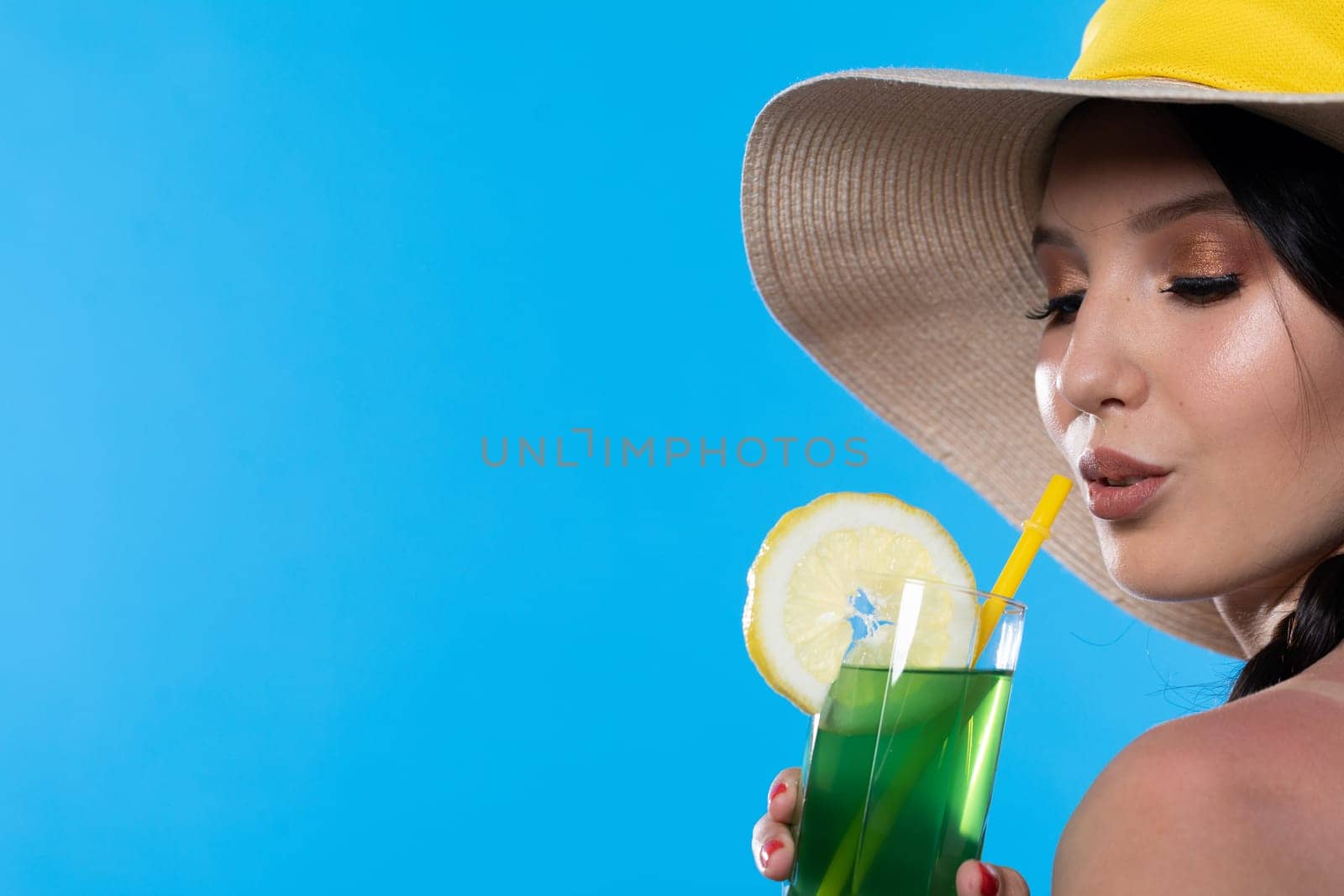 The young girl looks into the lens and holds a cold alcoholic drink in her hand.