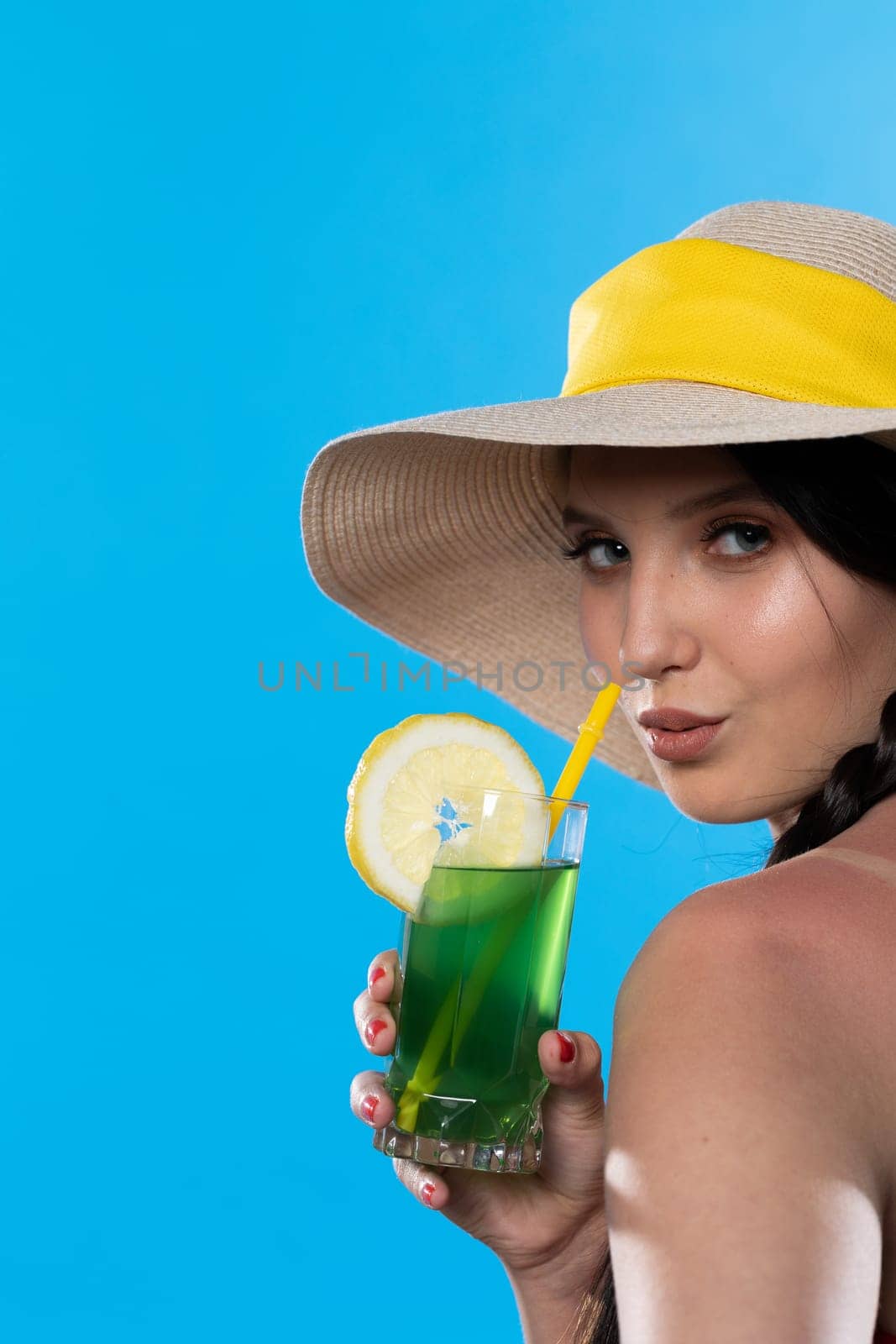 The young girl looks into the lens and holds a cold alcoholic drink in her hand.