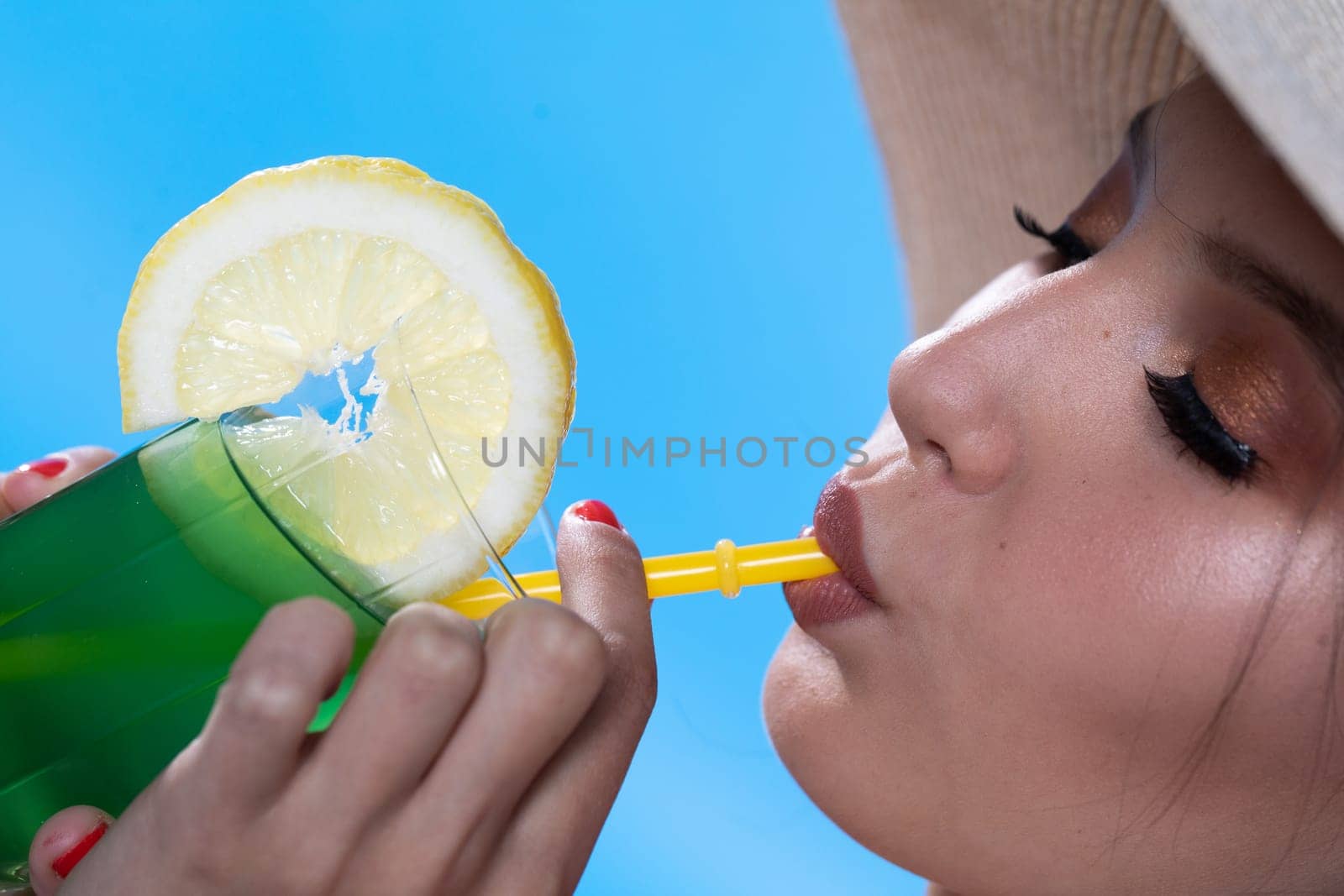 A teenager sipping a cold alcoholic drink through a straw during a hot summer.