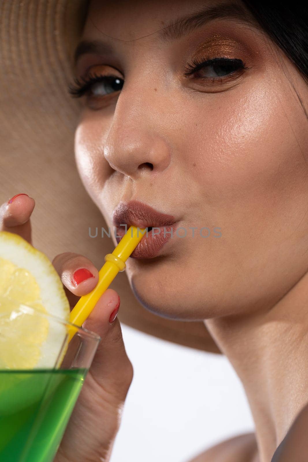 A teenager sipping a cold alcoholic drink through a straw during a hot summer.