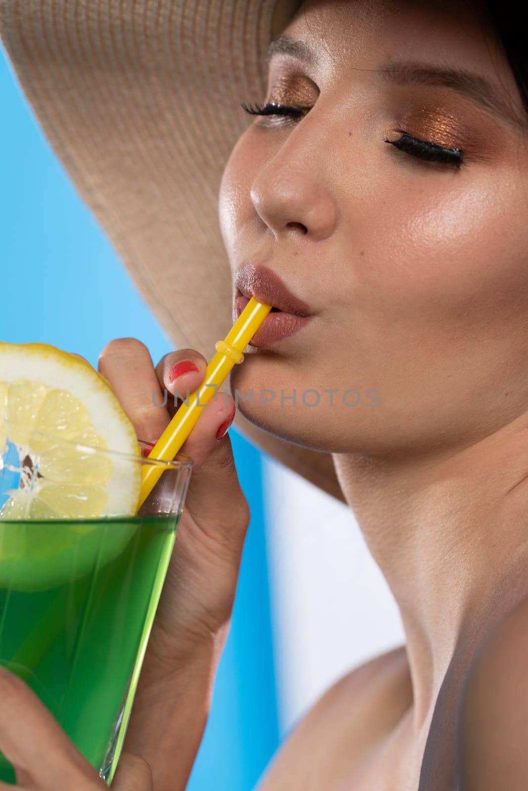 A teenager sipping a cold alcoholic drink through a straw during a hot summer.