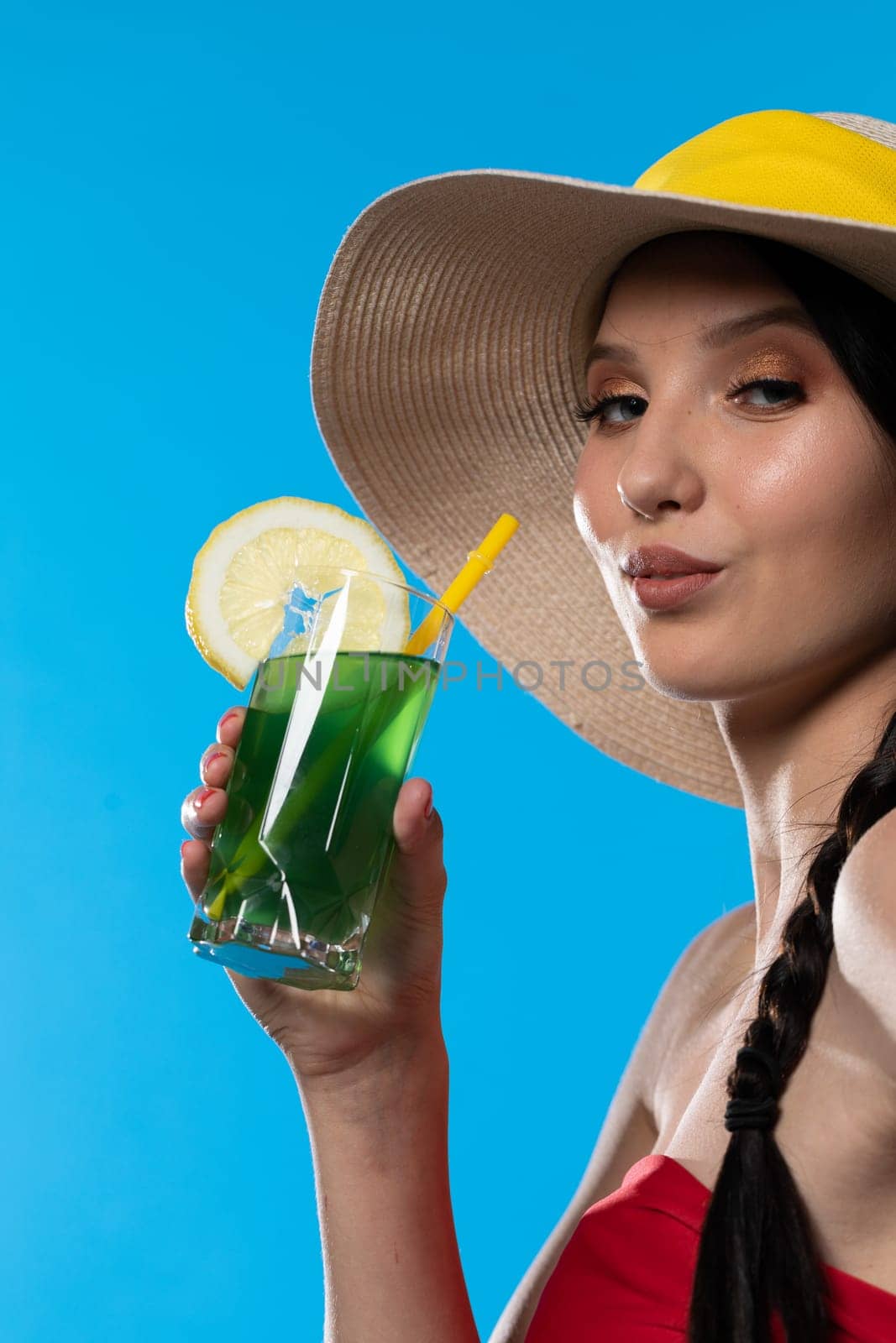 The young girl looks into the lens and holds a cold alcoholic drink in her hand.