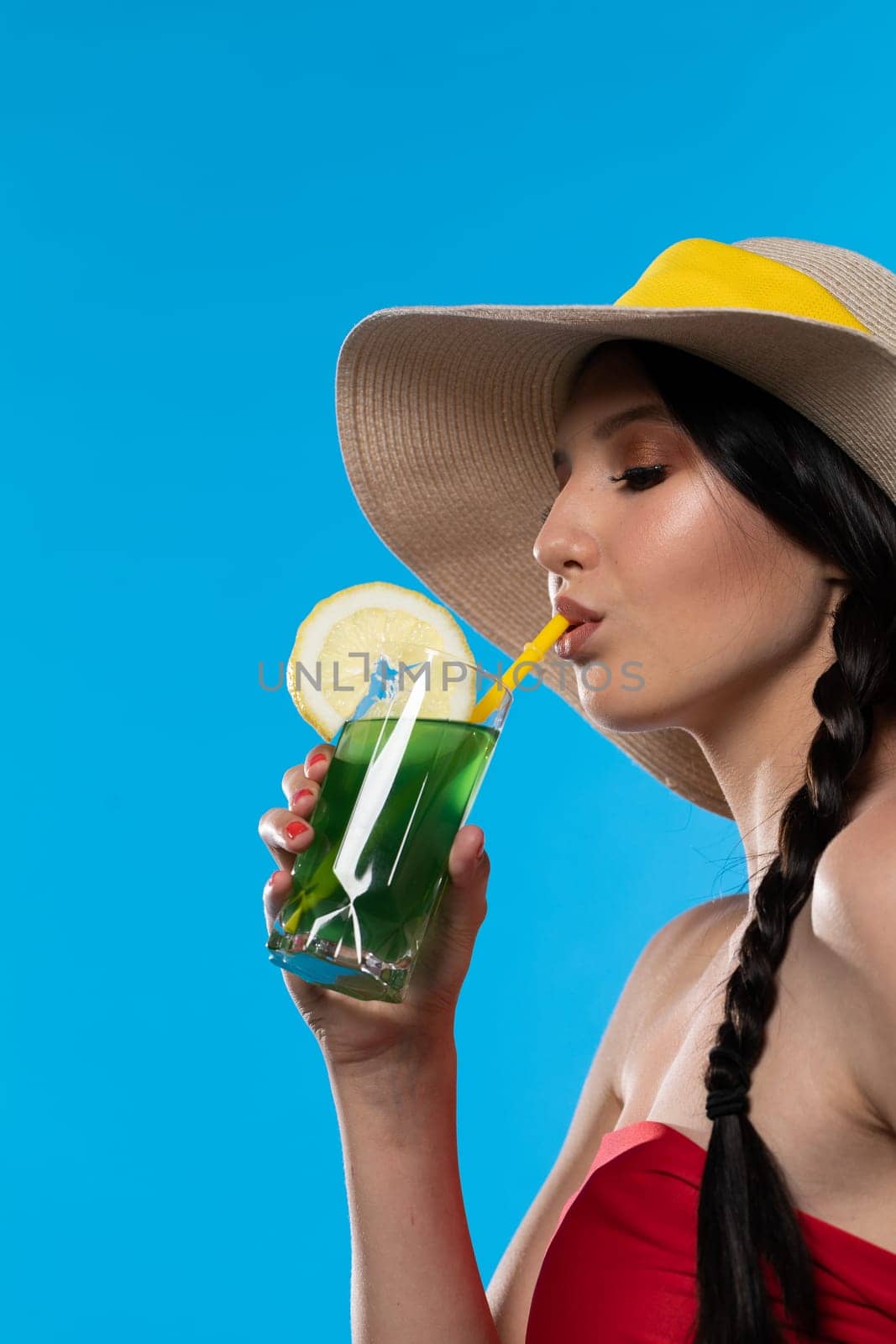 A teenager sipping a cold alcoholic drink through a straw during a hot summer.
