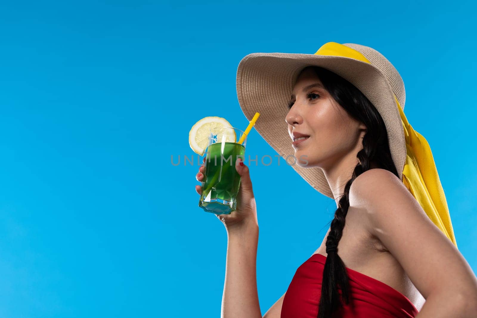 The young girl looks into the lens and holds a cold alcoholic drink in her hand.