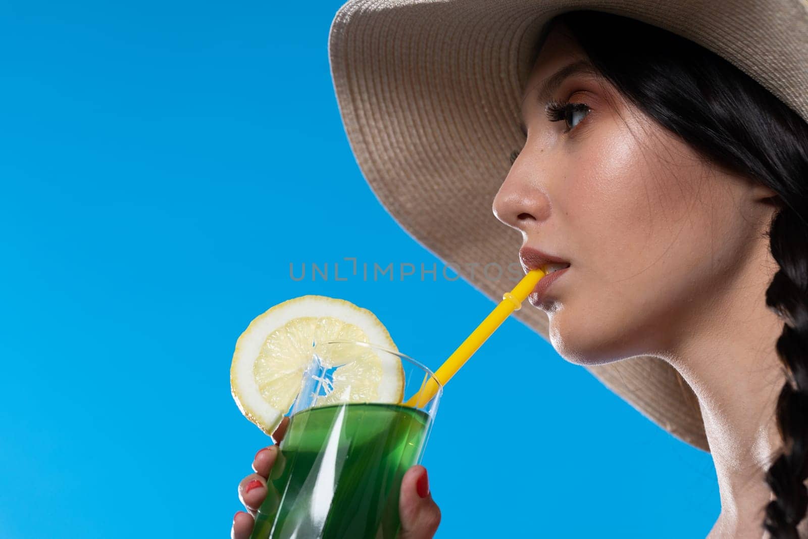 The young girl looks into the lens and holds a cold alcoholic drink in her hand.