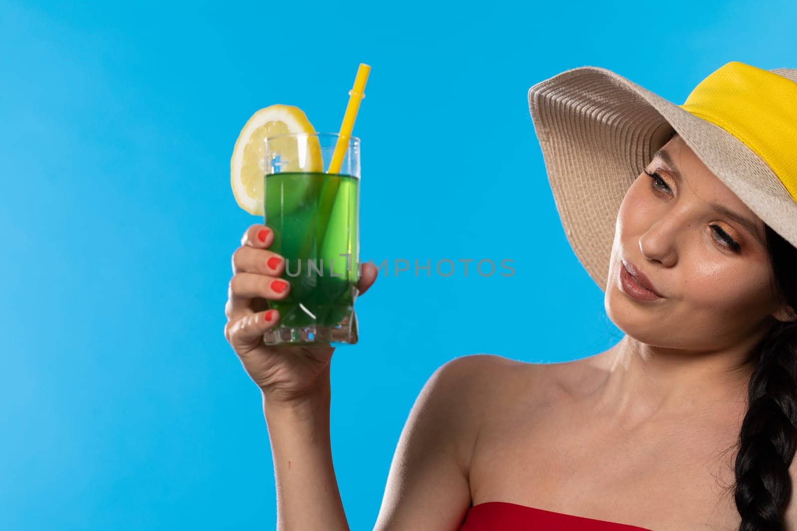 The young girl looks into the lens and holds a cold alcoholic drink in her hand.