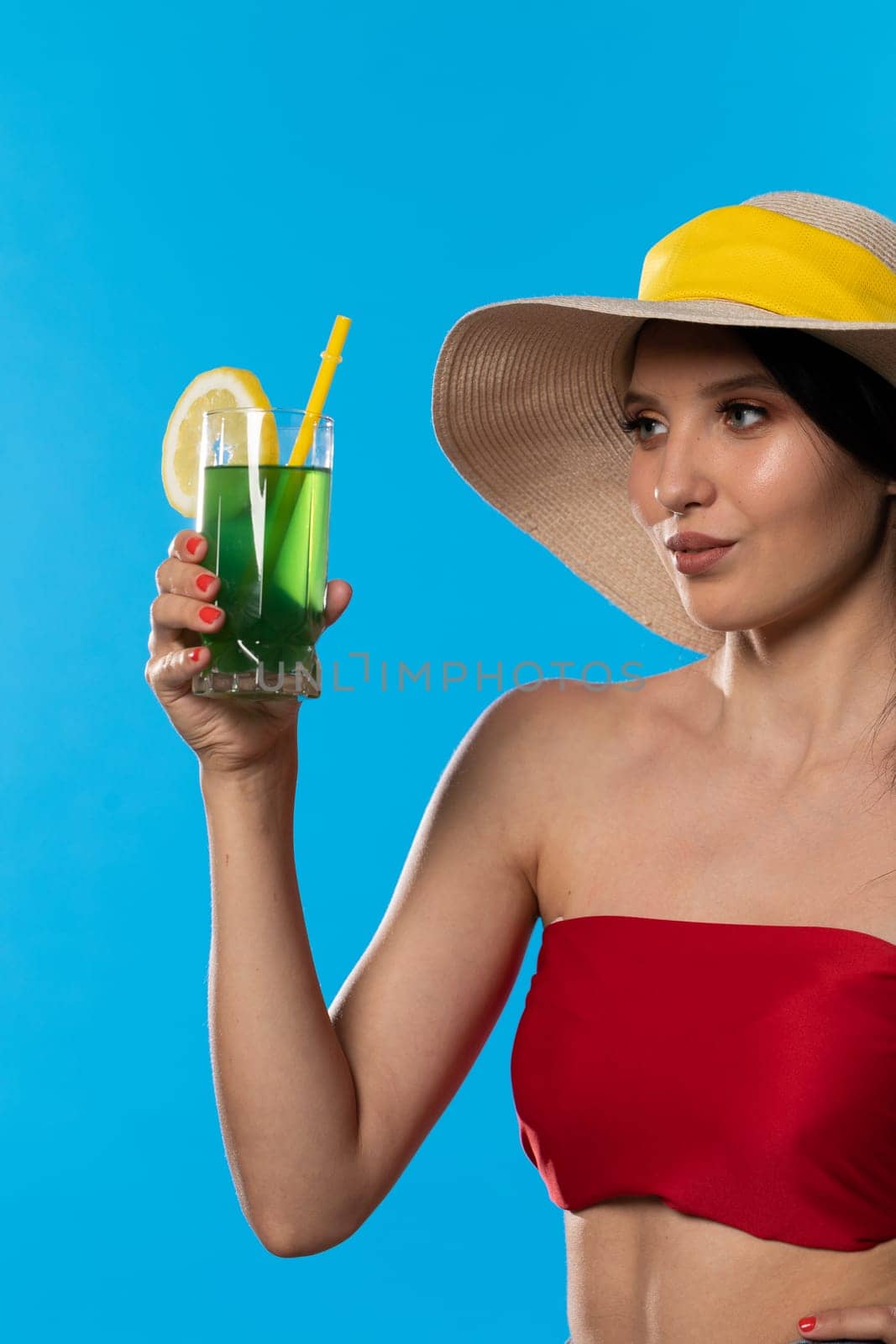 The young girl looks into the lens and holds a cold alcoholic drink in her hand.