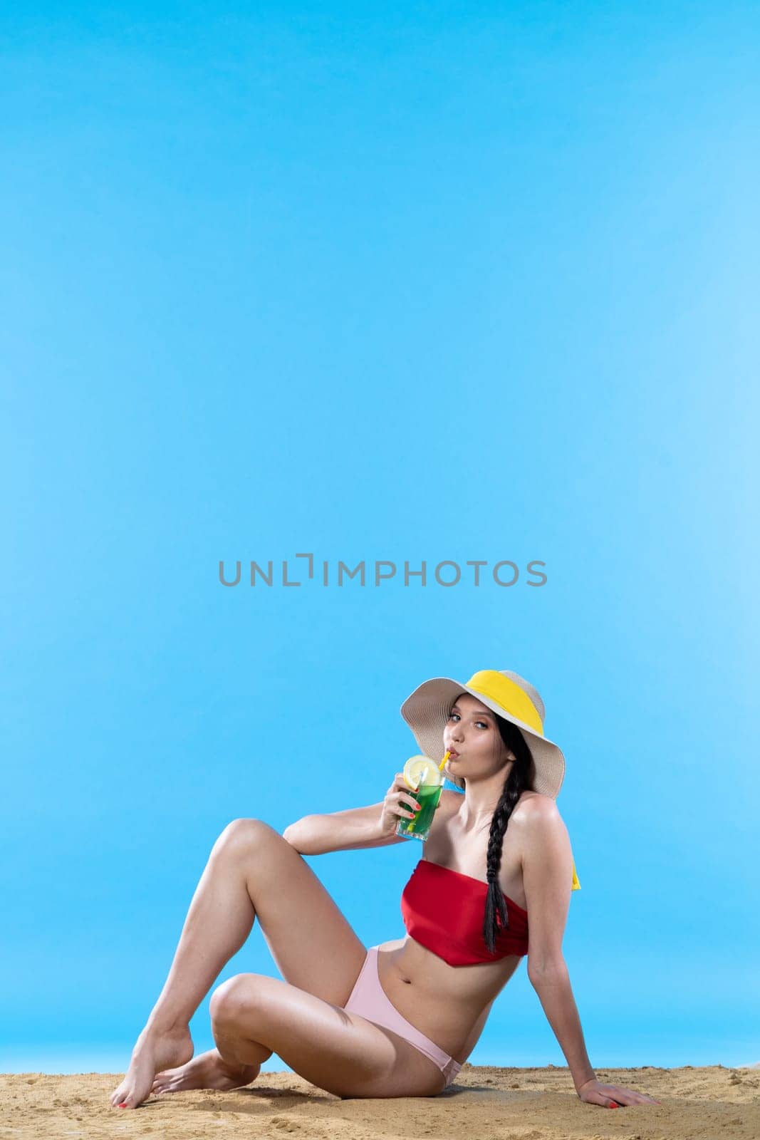 Teen sitting while sipping a cold alcoholic drink while enjoying the holiday sun. by fotodrobik