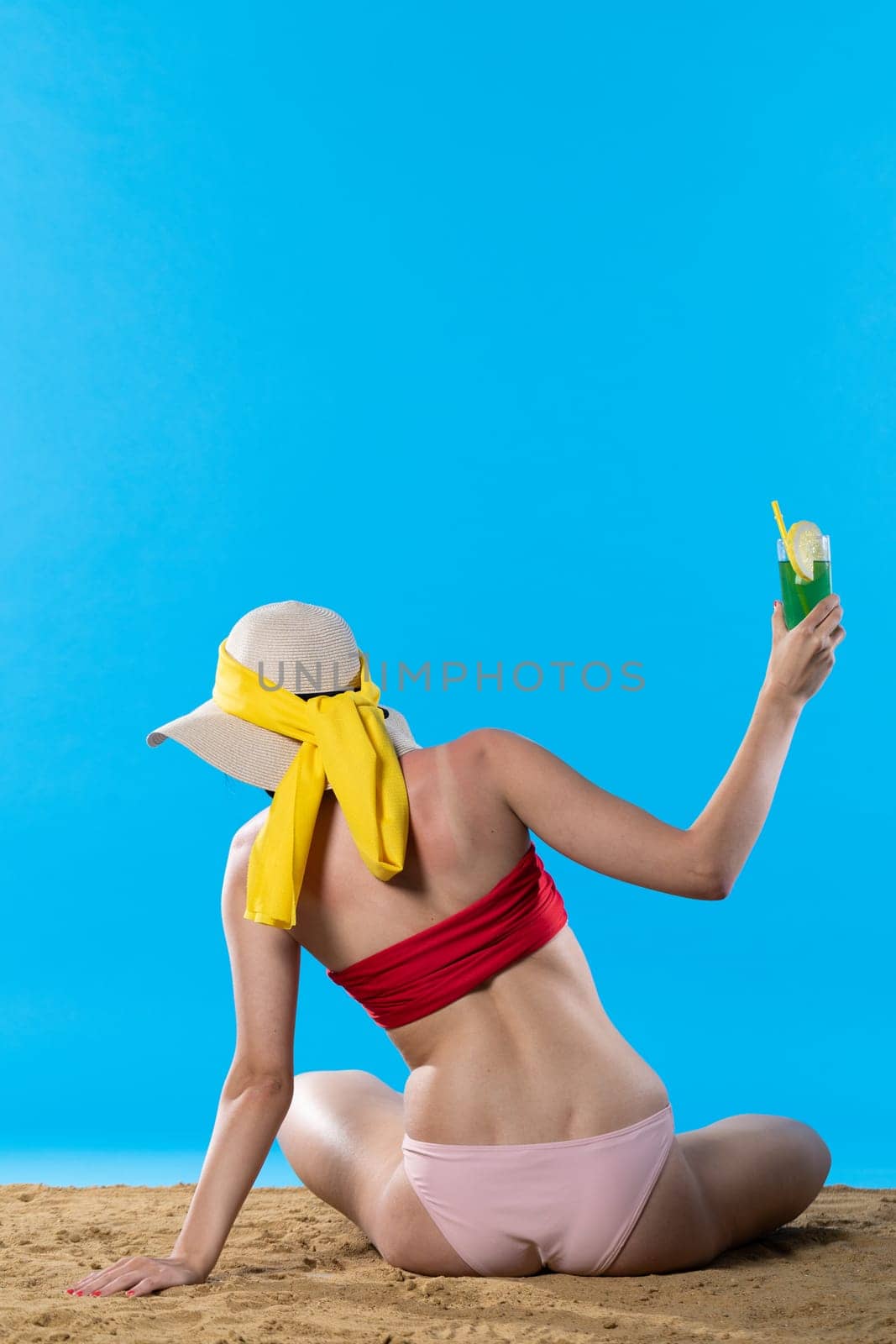 During hot summer, the teenager with a hat on her head holds an alcoholic drink in her hand.