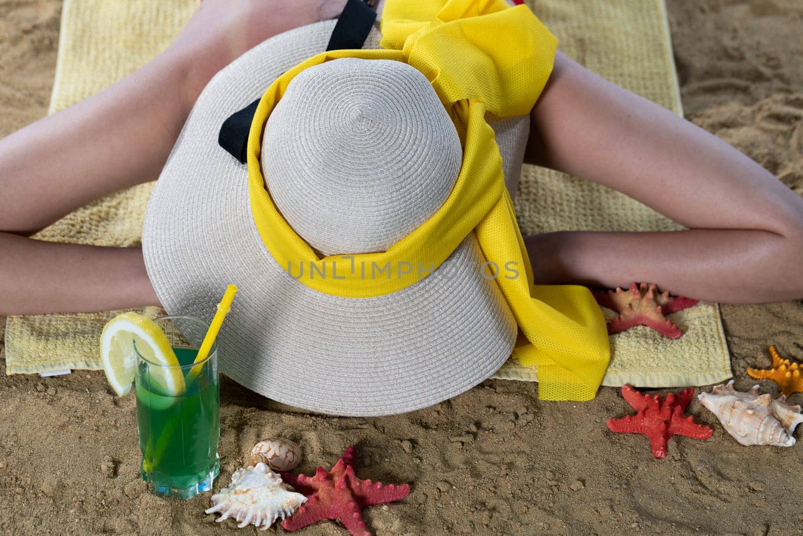 While sunbathing on the beach, a teenager drinks a cold alcoholic drink.