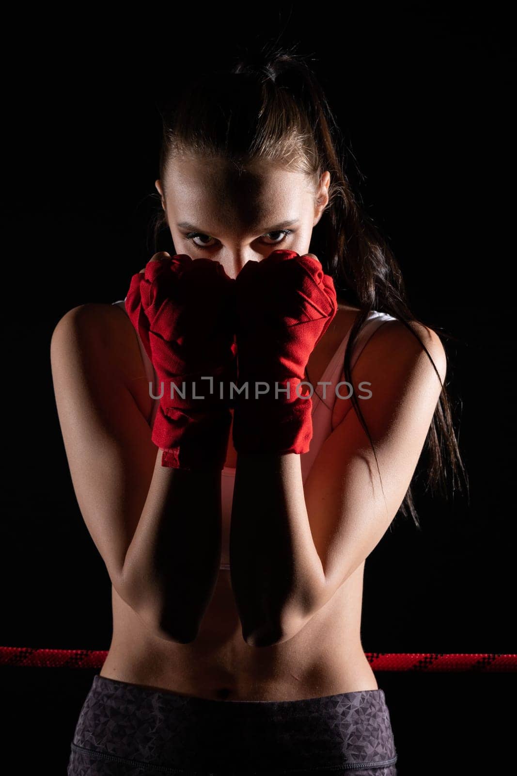 The head is hidden behind the strong guard of a professional sportswoman. A strong and athletic woman in the ring of sports.