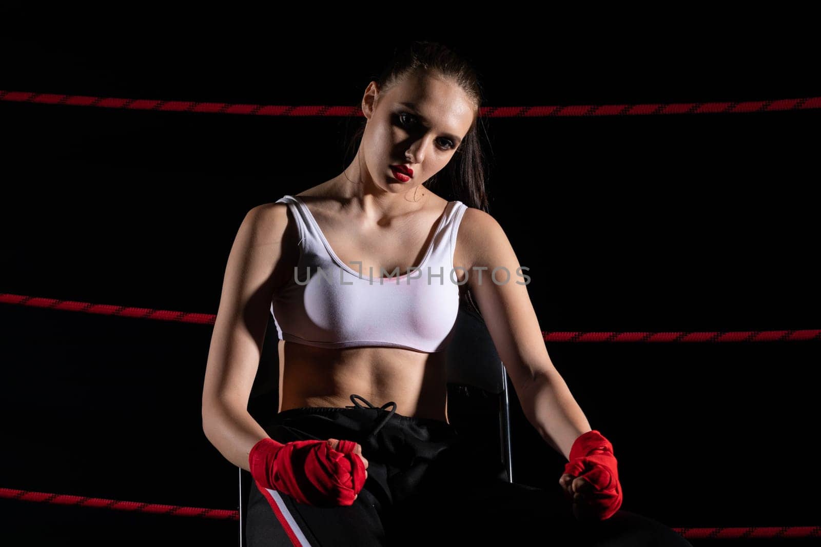 A lost fight of a strong player. He is sitting in a chair. Right after losing the fight. Sad woman after a fight in the ring.