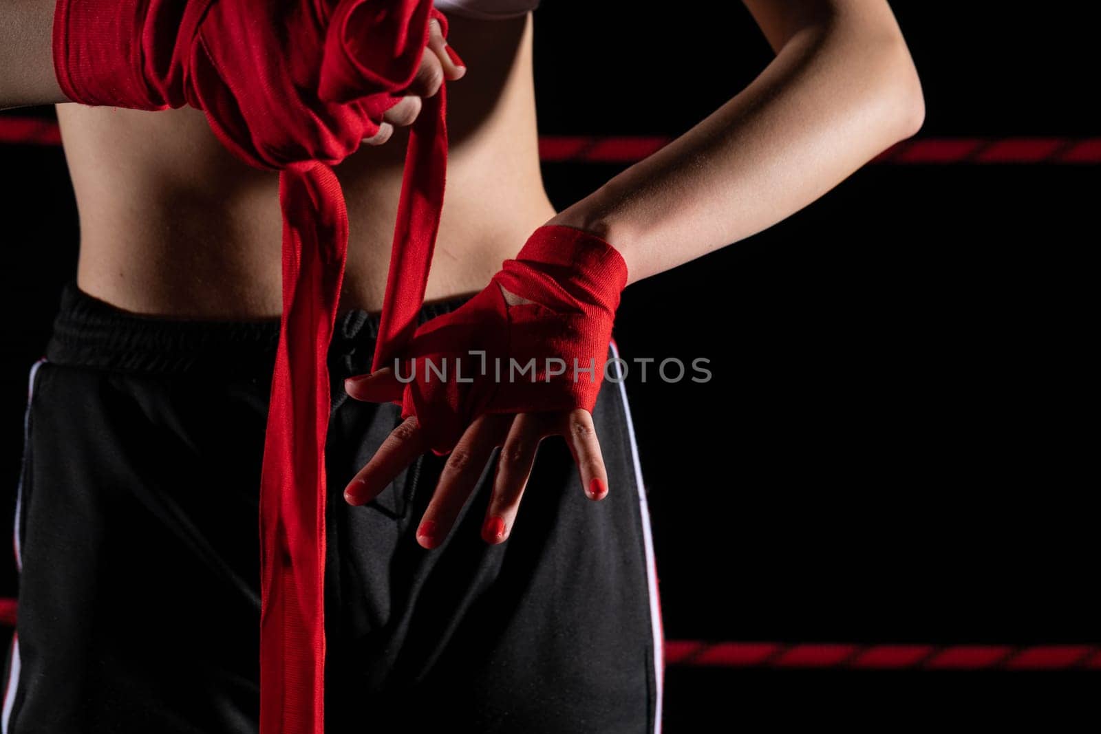 A woman prepares for an fight, wrapping her hands in a special boxing bandage. Strong woman. The inevitable fight in the ring.