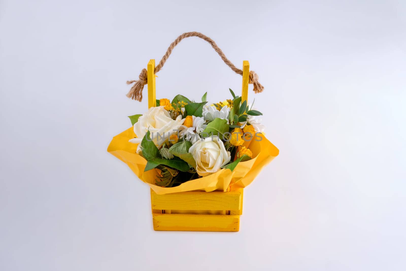 A bouquet of fresh flowers in a wooden basket on a light background