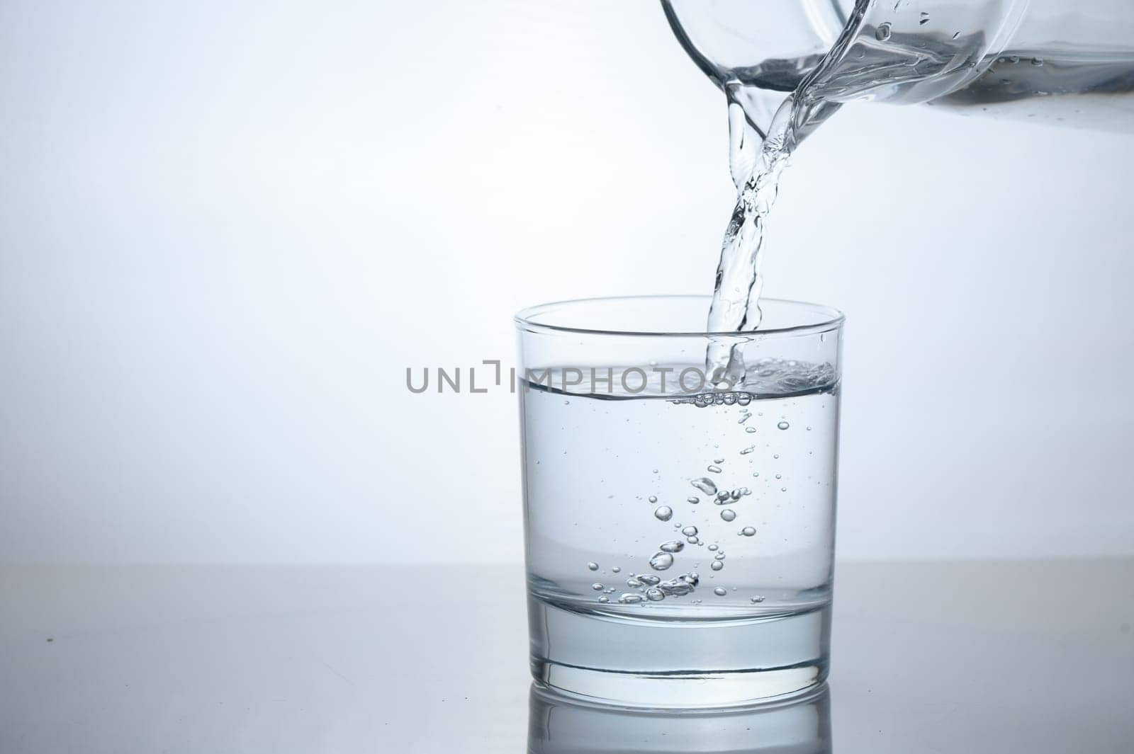 Purified water is poured from a glass jug into a glass.