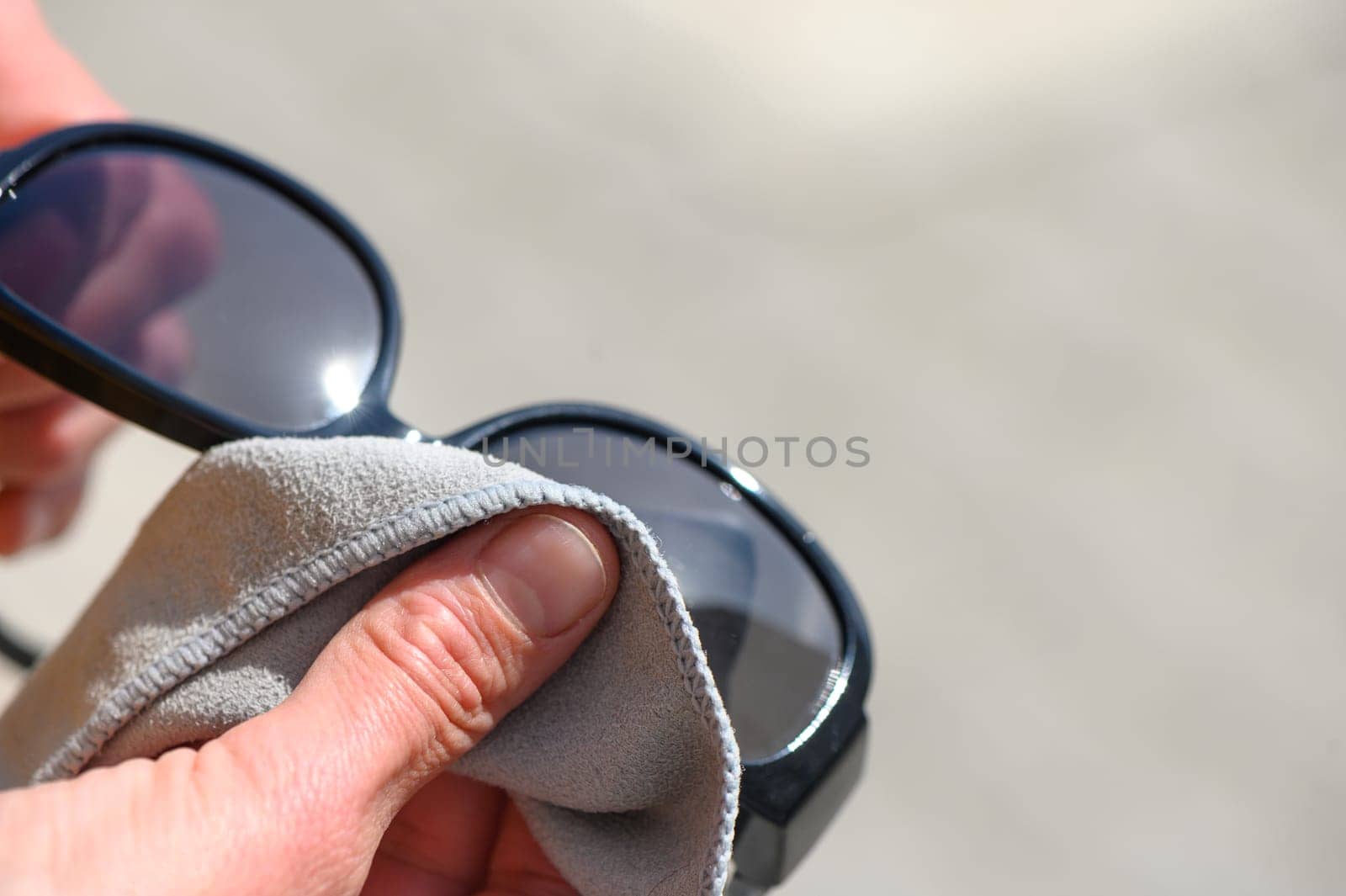 stylishly dressed young woman wipes sunglasses with microfiber, close-up view, high quality photo 3