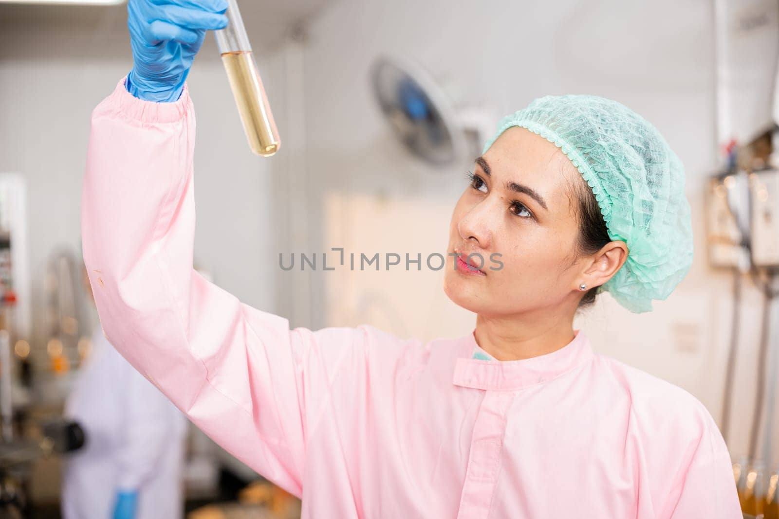 Woman food engineer demonstrates food and beverage quality and safety testing in juice beverage factory using test tubes to sample basil or chia seeds in bottled expertise in laboratory control.