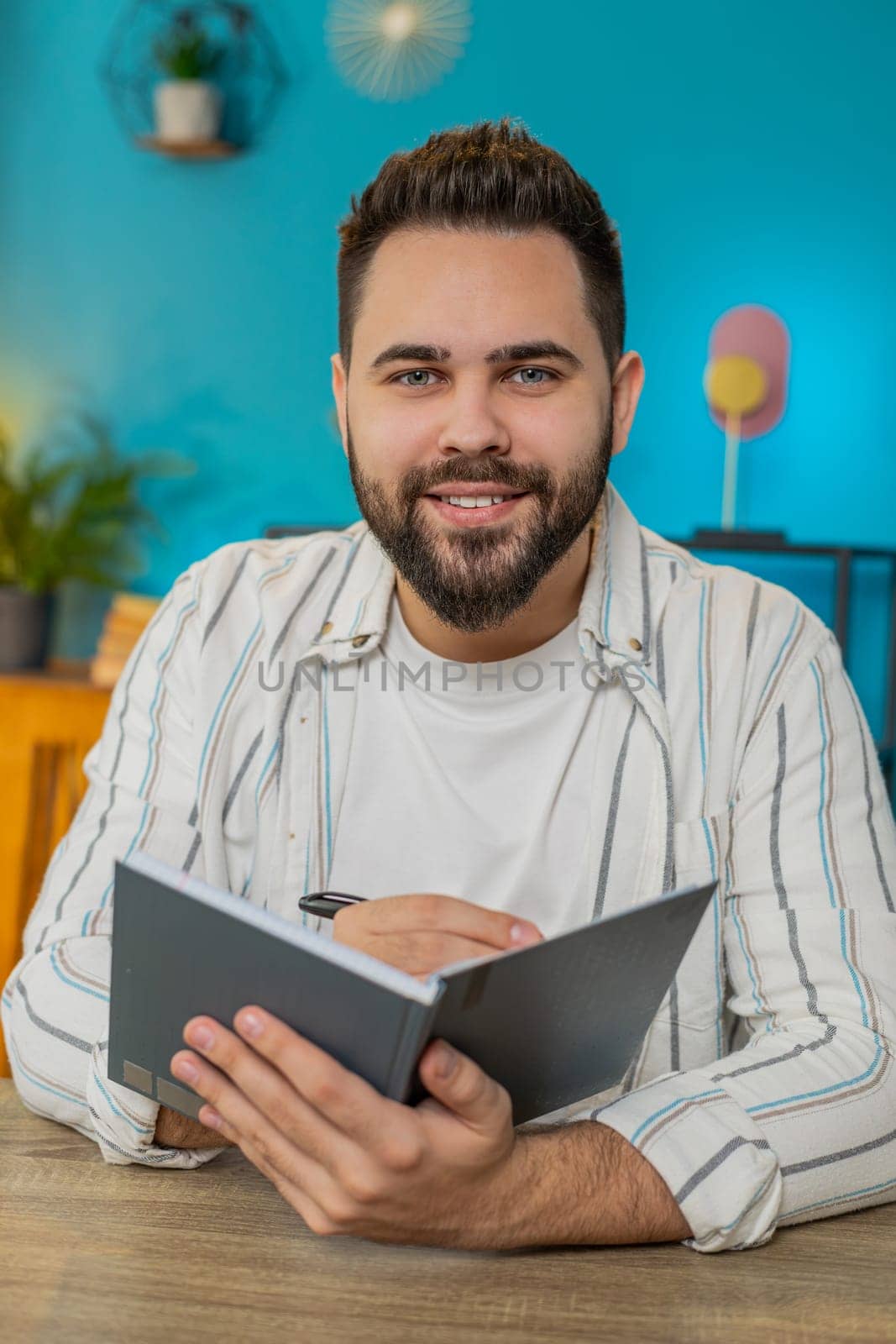 POV laptop view of freelancer man study with notebook making notes. Guy making conference video call talking to webcam sits at home office table. Online education e-learning in remote chat. Vertical