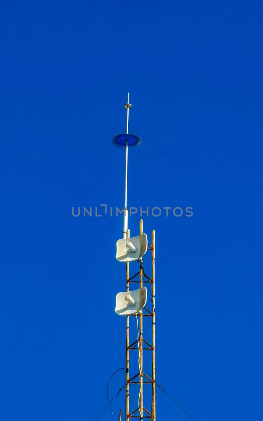 Red white 5G tower with blue sky background radiation kills us in Zicatela Puerto Escondido Oaxaca Mexico.