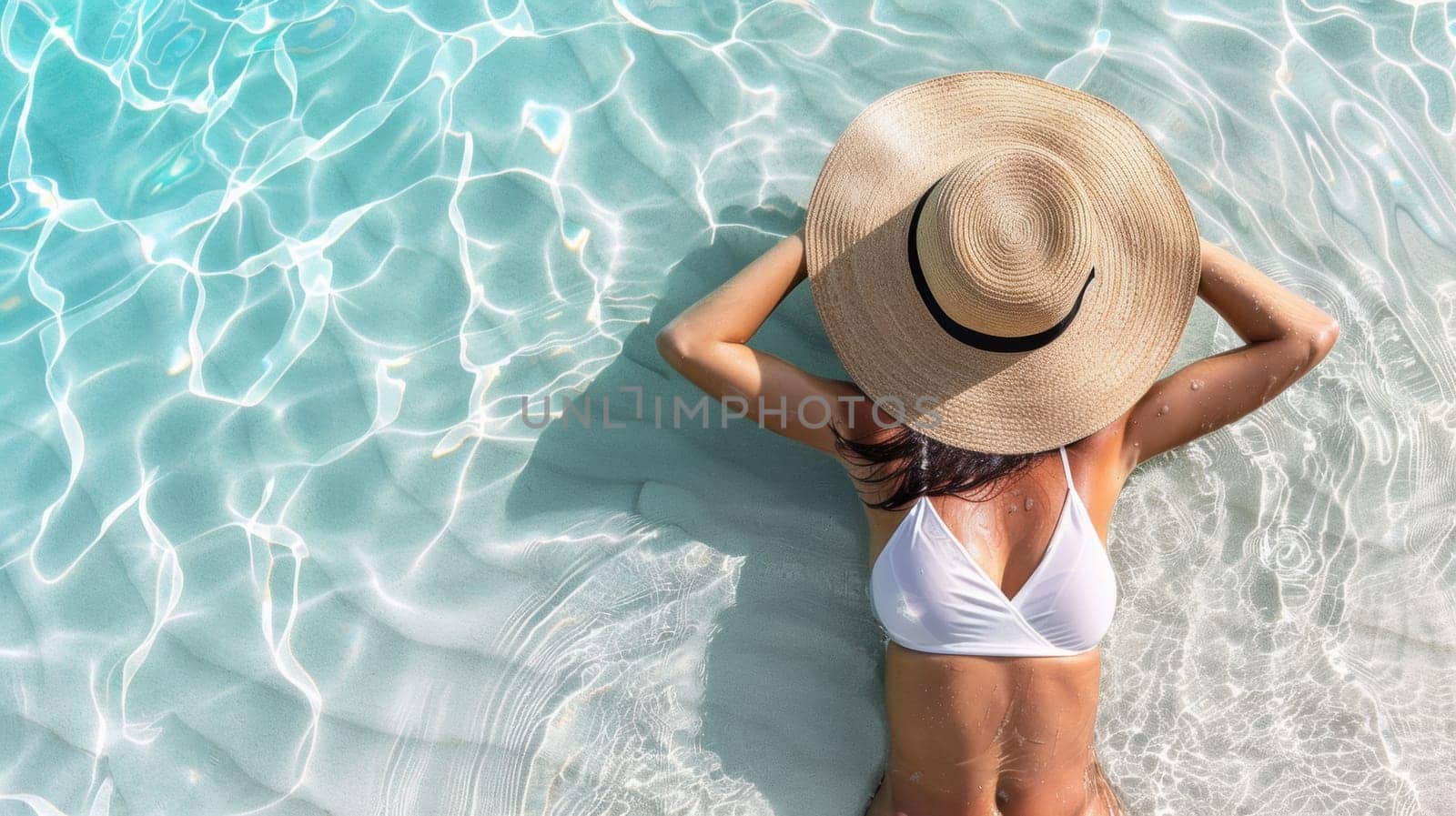A woman in a bikini and hat floating on the water