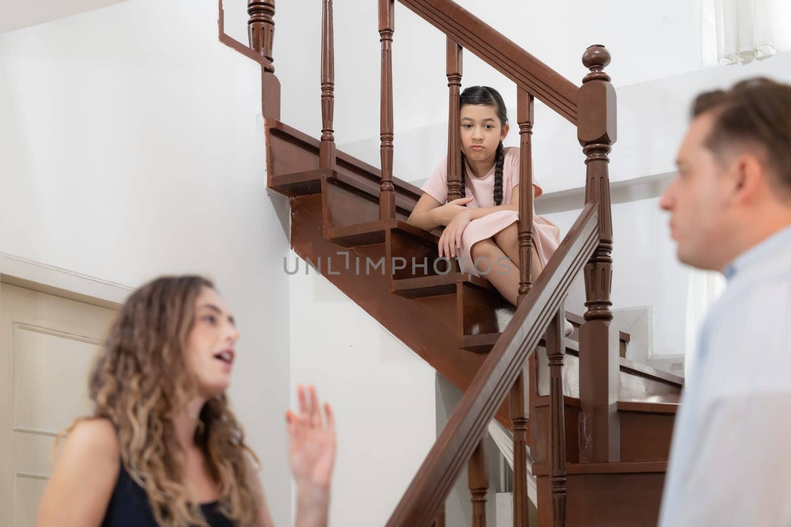 Stressed and unhappy young girl watch her parent arguing from the stair. Domestic violence at home and traumatic childhood develop to depression and anxiety. Unhealthy family concept. Synchronos