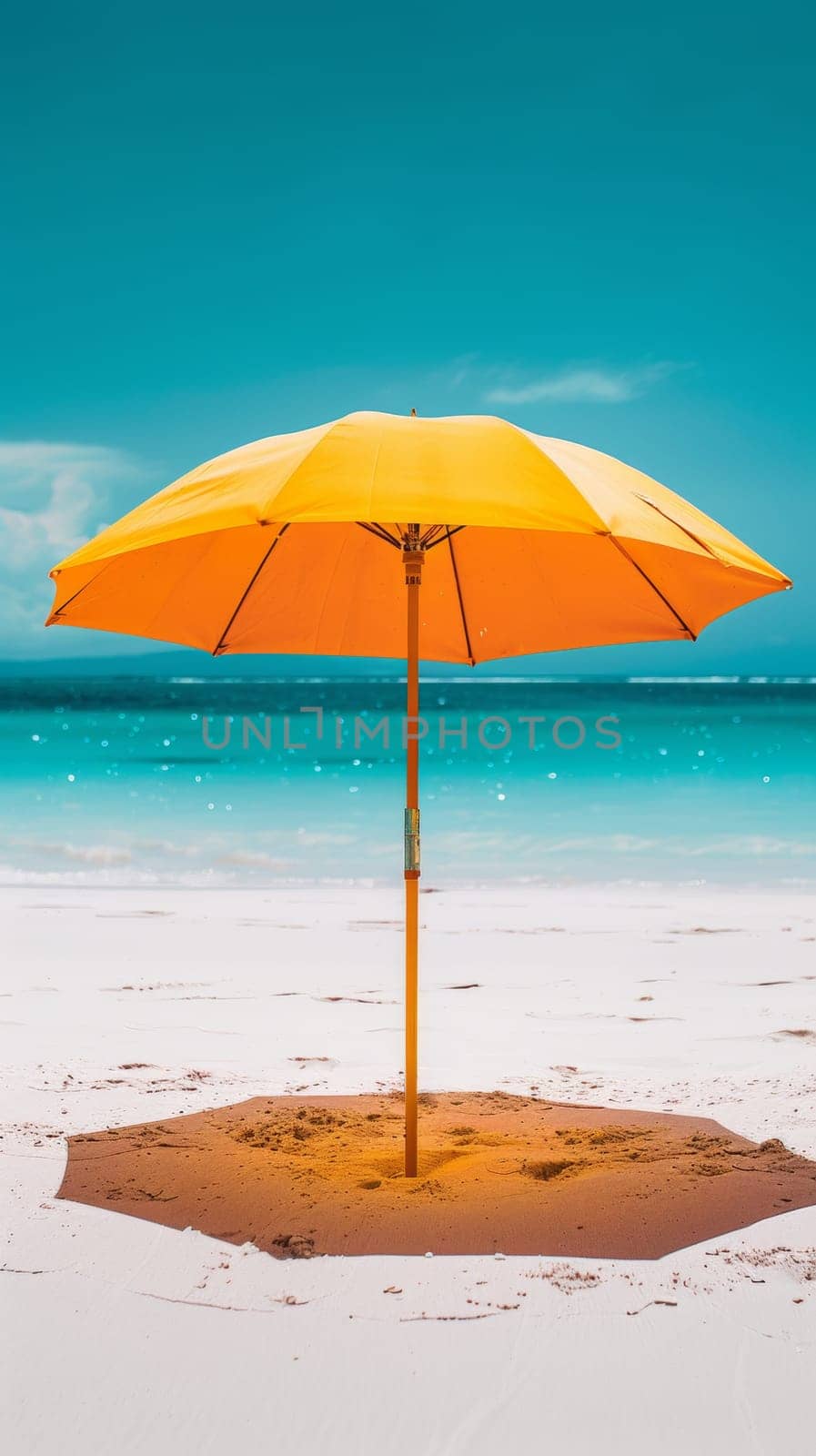 A yellow umbrella on the beach with a blue sky and ocean