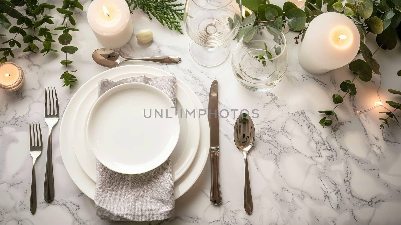 A white table setting with silverware, plates and candles