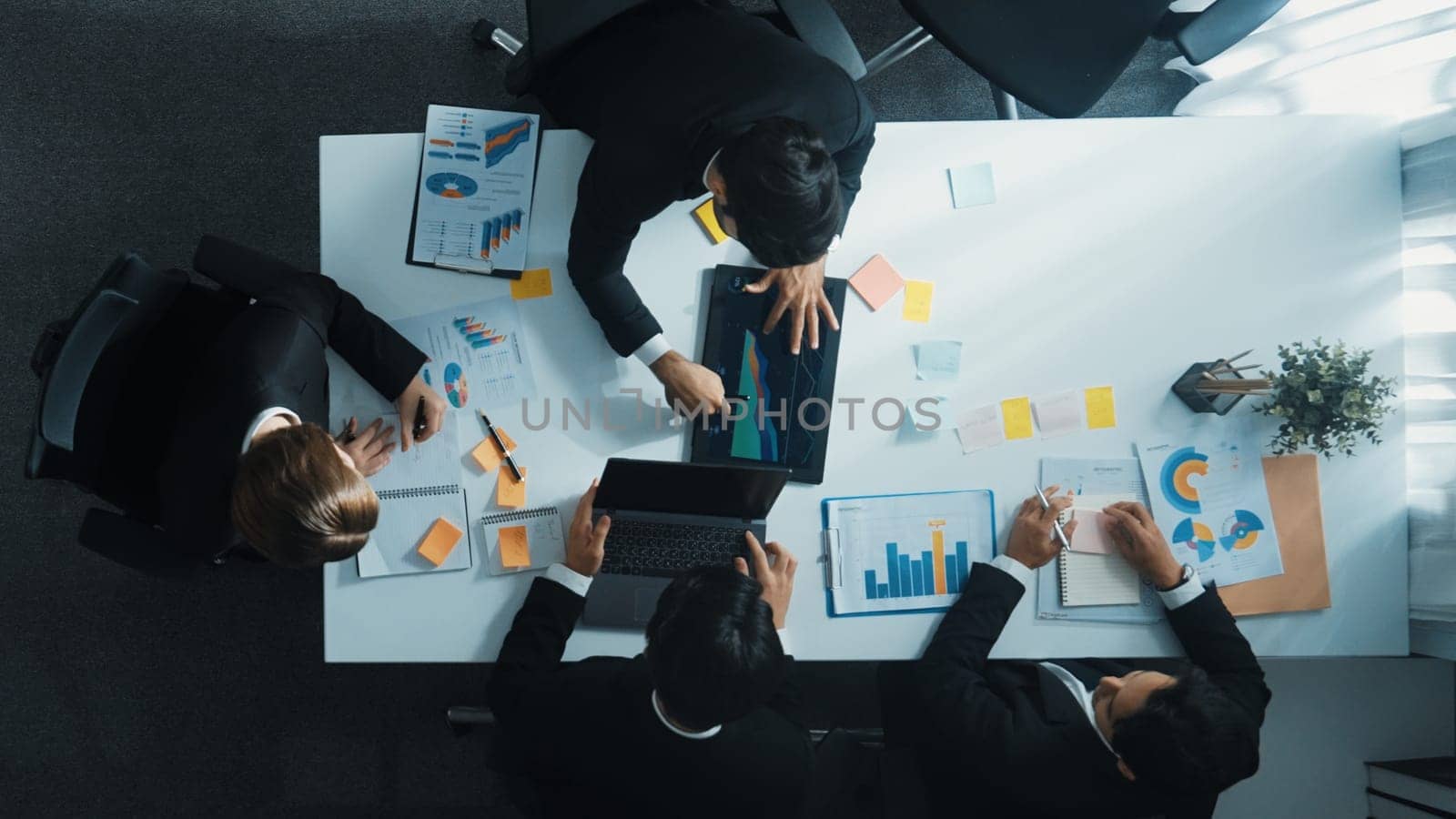 Top down aerial view of manager standing and present marketing plan to skilled investor. Diverse business team working together to analyze financial statistic graph at meeting table. Directorate.